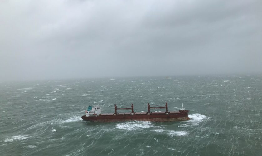 Een groot vrachtschip drijft stuurloos op een stormachtige zee.
