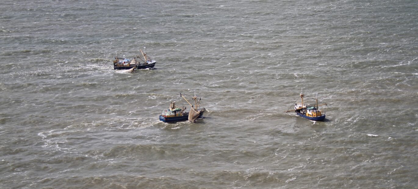 Drie vissersschepen zijn op zee gefotografeerd vanuit het Kustwachtvliegtuig. Aerial officers aan boord van het Kustwachtvliegtuig houden toezicht op de naleving van regels voor de visserij.