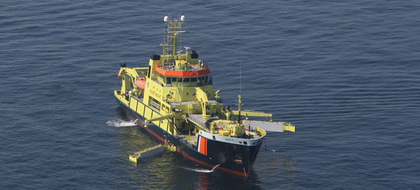 Oliebestrijdingsvaartuig Arca vaart op zee met twee armen aan de zijkant uitgeklapt om zo olie op te kunnen ruimen.