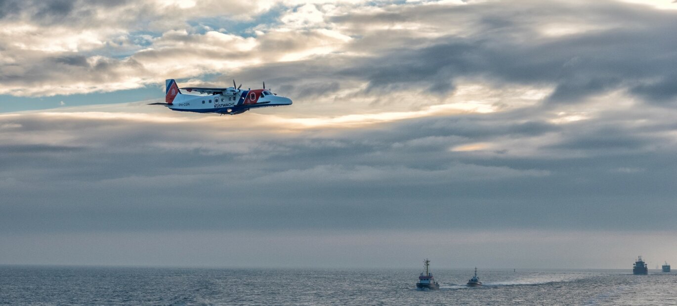 Het Kustwachtvliegtuig vliegt over de Noordzee en houdt toezicht op de scheepvaart.