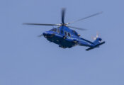 De blauwe politiehelikopter AW139 vliegt door een strak, blauwe lucht.