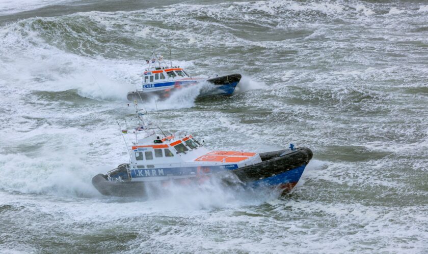 Twee grote reddingboten van de KNRM varen op een stormachtige zee.
