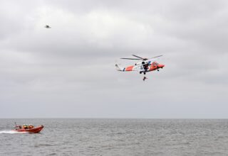 De kustwachthelikopter hijst een persoon uit het water.